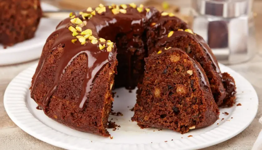 Pyszna babka na oleju, polana czekoladą i posypana pistacjami, czeka na kawę.